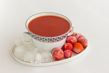 Summer cold tomato soup (gazpacho). Ice and frozen tomatoes on a plate, white background.