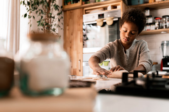Concentrated black child with biscuit in kitchen
