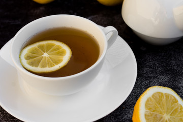 Teapot and cup of tea with fresh lemon.