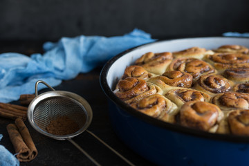 Cinnamon roll tart with sugar syrup in vintage baking pan on black background