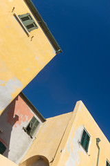 Fototapeta na wymiar Close up view of yellow houses in Varigotti against blue sky. Varigotti is a small village along the seaside in Italy