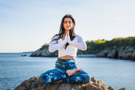 Young Woman Doing Yoga On The Rocks At Golden Hour