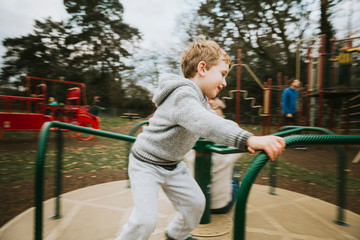 Side view of child on merry go round at playground