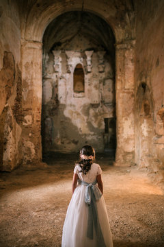 Little girl in communion dress in n old convent in ruins