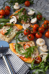 Homemade pizza with rucola and cherry tomatoes.
