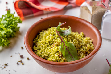 Couscous in bowl with olive oil and dried tomatoes on white background, oriental cuisine, horizontal orientation
