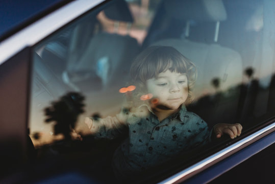 Toddler boy in driver's seat of van looking at the sunset