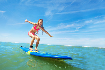 Happy beautiful girl learn to surf on surfboard