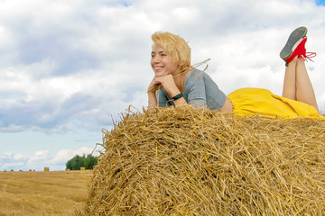 Naklejka na ściany i meble Young beautiful woman on a background of haystacks in field