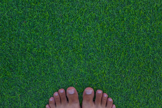 boy feet toes on outdoor green synthetic grass top view wallpaper background picture with empty copy space for your text
