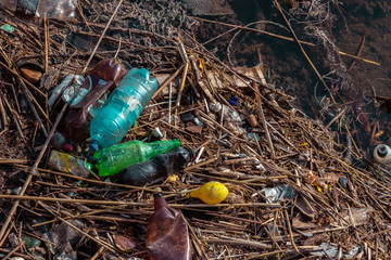 Garbage floating in the water. River in the big city polluted with various garbage and trash. Empty used dirty plastic bottles in dirty river water. Environmental pollution. Ecological problem.
