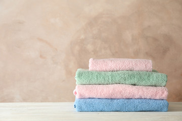 Stack of clean towels against brown background, space for text