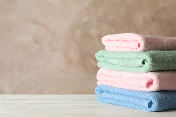 Stack of clean towels against brown background, space for text