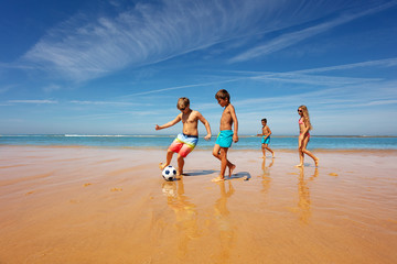 Kids in the middle of soccer game play on a beach