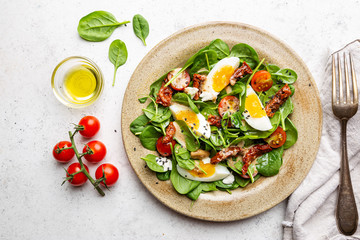 Salad with spinach, sun-dried tomatoes and eggs. Healthy home made food. Concept for a tasty and healthy meal. Top view. Copy space.