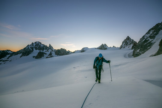 An alpinist uses a trekking pole on flat glaciated terrain pre-dawn