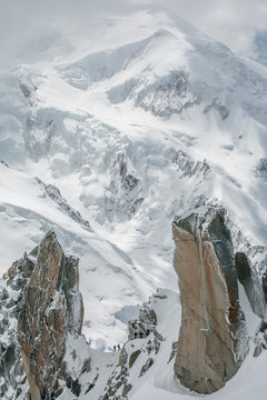 Two alpinists on Cosmiques are dwarfed by Mont Blanc in the background