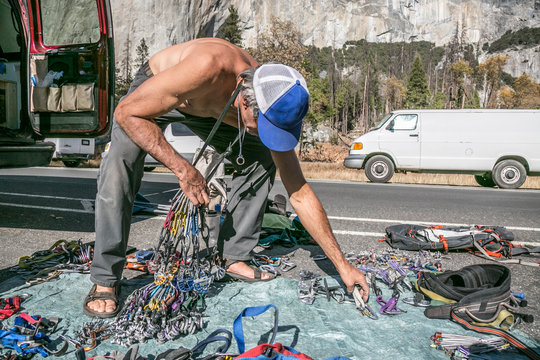 A shirtless climber sorts gear prior to a climb of el Capitan