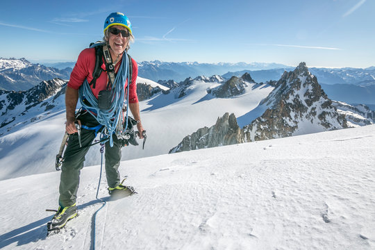 A seasoned alpinist full of stoke on a bluebird day in the French alps