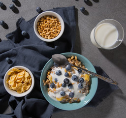 Breakfast. Granola with blueberries and a glass of milk on a gray background top view