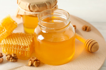 Honeycombs, walnuts, dipper and jars with honey on wooden background, closeup
