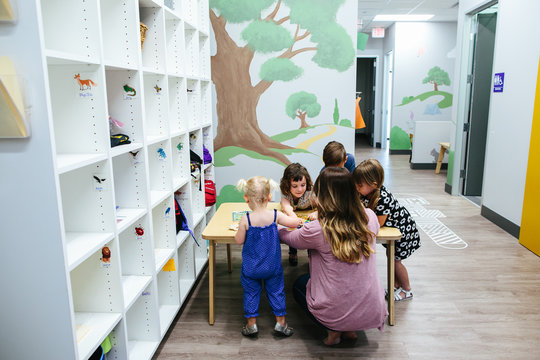 Children gather at a table with teacher at school