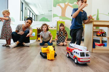 Kids on the ground at a school racing toy cars