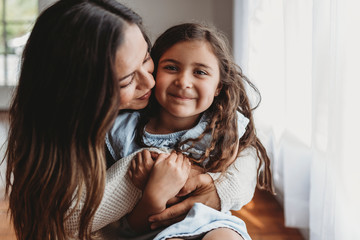 Portrait of little girl smiling while mother embraces her