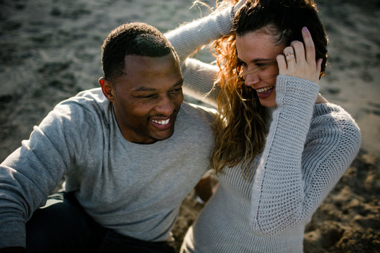 Couple laugh on beach at sunset