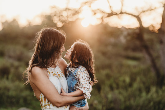 Side view of mother and daughter embracing in sunny field