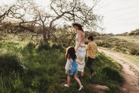 Side View Of Mother And Children Walking Into Field Together