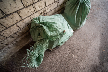 Green cloth trash bags in the alley near the wall
