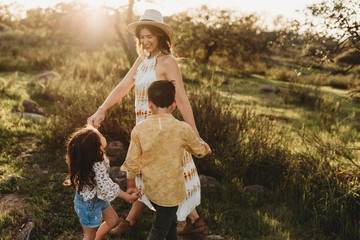 Close up of mother in hat playing ring around the rosie with children