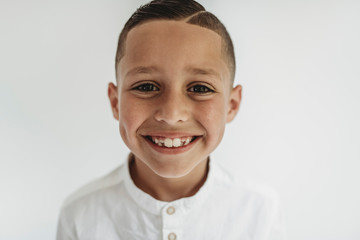 Portrait of young school-aged boy smiling in studio