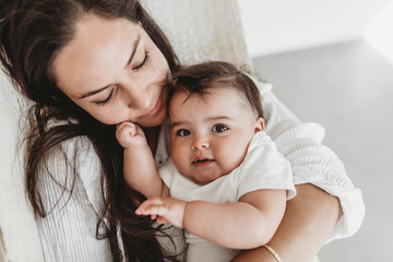Mother and baby daughter cuddling in hammock in natural light studio