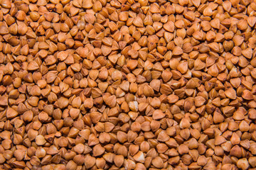 Background texture of whole grains of buckwheat. Image food product porridge buckwheat grains. Soft selective focus.