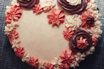 Pink cake with cream flowers on a dark background