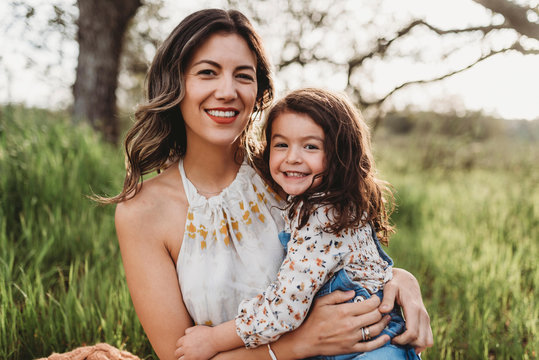 Portrait of mother and daughter in backlit field smiling at camera - Powered by Adobe