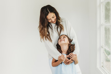 Mother and daughter looking at each other in natural light studio
