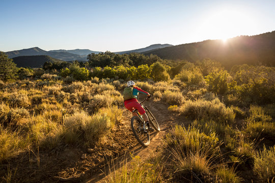 A woman riding a mountain bike outdoors just before sunset - Powered by Adobe