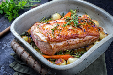 Traditioneller gebratender Kalbsrücken angeboten mit Karotten und Zwiebel als closeup in einem Topf