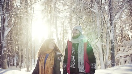A portrait of couple standing outdoors in snow in winter forest, throwing snow. - Powered by Adobe