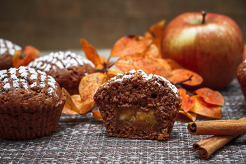 Chocolate muffins with apple filling on a background of autumn leaves and cinnamon