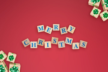 New year or Christmas holidays composition on red background with text merry christmas in center of wooden cubes.