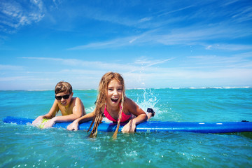 Fototapeta na wymiar Brother and sister swim for fun on surf board