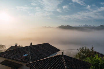 houses on a hillside with fog and mountains in the background at dawn