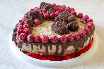Heart shaped vegan raspberry coated chocolate cake on white kitchen table. Top angle view. Selective focus.