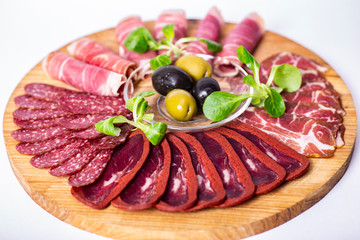 Food tray with delicious salami, pieces of sliced ham, sausage and olives. Meat platter.