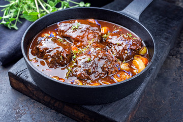 Traditional German braised beef cheeks in brown red wine sauce with carrots and onions offered as...
