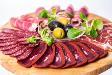 Food tray with delicious salami, pieces of sliced ham, sausage and olives. Meat platter.